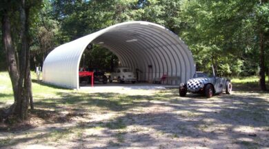 S-Model Quonset hut with no end walls, a checkered race car in front, a white Buggy inside, another car inside, and a red bench inside.