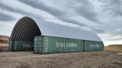 long shipping container cover structure with two green conex boxes next to each other